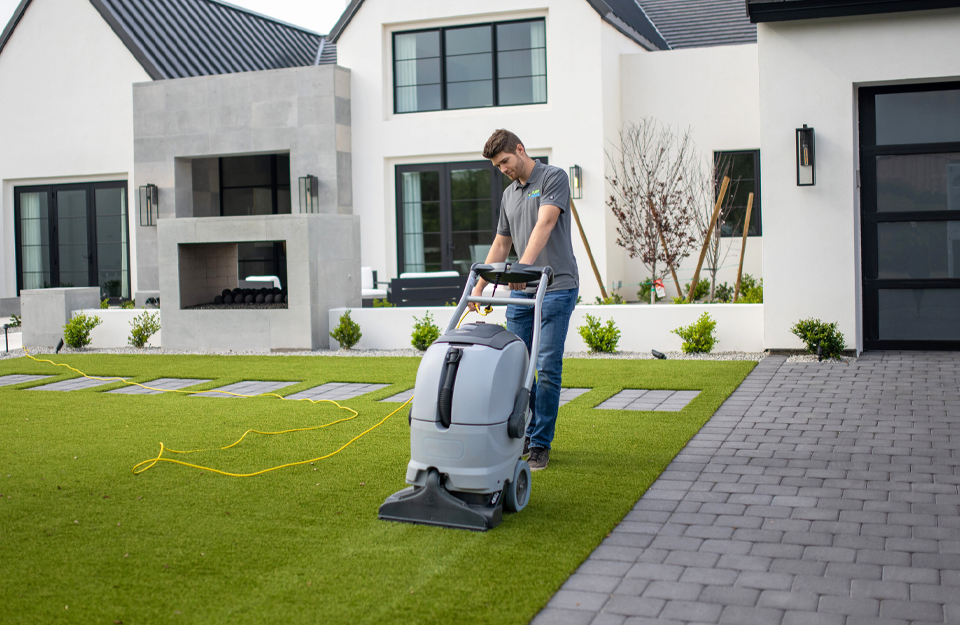 Man disinfecting and cleaning artificial grass lawn in Phoenix, AZ